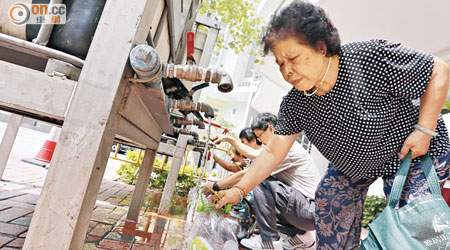 政府安排臨時水箱給居民，長者俯身取水時顯得辛苦。