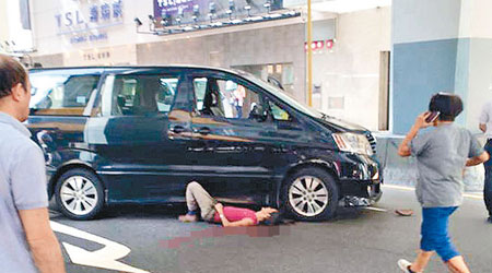報檔東主半邊身體困在車底，妻子（右）聞訊趕到現場。 （互聯網圖片）