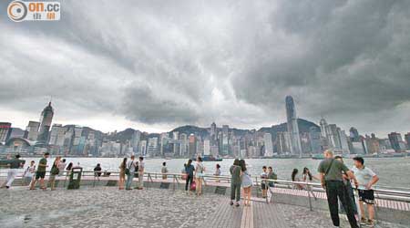 天文台昨連發兩黃一紅暴雨警告，市民趁天氣稍好轉，往海邊欣賞維港景色。（胡家豪攝）