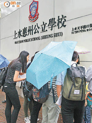 家長在黃色暴雨警告下到上水惠州公立學校外排隊等候交表。（蘇文傑攝）