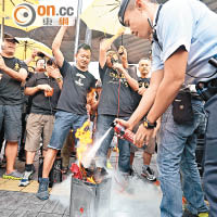 有人民力量成員焚燒寫有抗議標語的畫紙，遭警員用滅火筒撲熄。（陳章存攝）