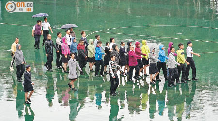 醫療輔助隊隊員在風雨下，仍在繼續綵排。（洪業銘攝）