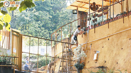 一名男子在定慧寺大門加裝兩支閉路電視錄影鏡頭。（林少兒攝）