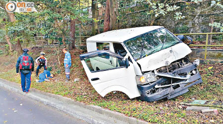 客貨車溜後剷上草坪，車頭損毀，受傷乘客臥地待援。（文健雄攝）