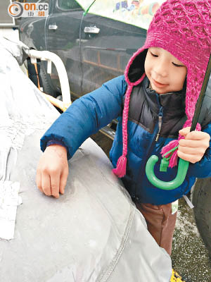 元朗 <br>本港持續錄得低溫，寒潮料加劇，小朋友好奇拾起小冰粒。（讀者提供）