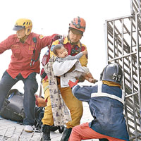 救援人員在倒塌樓宇內救出一名小童。（互聯社圖片）