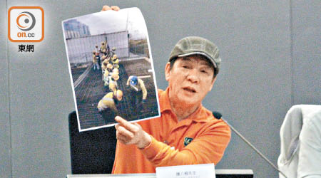 陳八根高舉十四名工人抬鐵枝的照片，證明本港不缺乏建造業工人。（何天成攝）