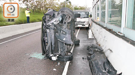 首宗車禍的私家車撞壆後翻側。（胡德威攝）