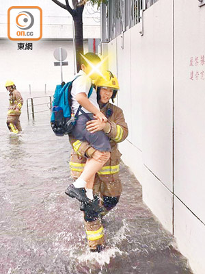 深水埗<br> 保母車因水浸而死火，消防員逐一抱着男童涉水走過一段水浸的道路。（「小心駕駛（討論別人駕駛態度）」fb群組）