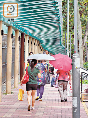大埔<br>由港鐵大埔墟站通往富雅花園的透明行人路上蓋，未能遮擋陽光，居民要撐傘而行。