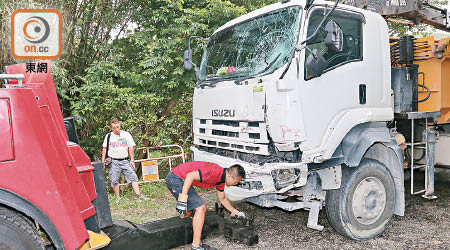 泥頭車左車頭損毀，司機（左）一臉無奈。（黃永健攝）