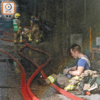 消防坐在災場地上，神情顯得沮喪。