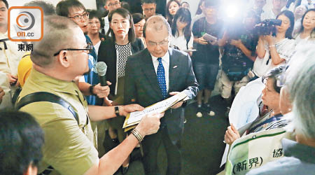 請願人士會議前向張建宗遞交低津申請表道具，諷刺福利政策遠落後實際需要。（陳章存攝）