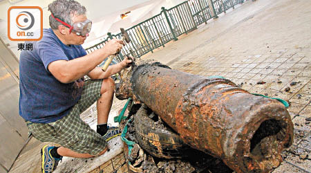 博物館修復員夏保羅小心翼翼用錘仔鑿開包裹着大炮的銹蝕物。