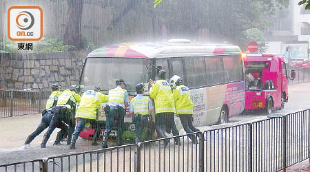 七名警員合力將邨巴推離地陷路面。（曾志恒攝）