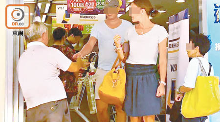 伸手索取<BR>一名長者（左）手持超市印花，向外國人示意，希望對方可送贈印花。