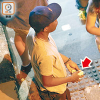 一名非洲裔男子常駐守德己立街的便利店旁樓梯，拿着包着物體的白色紙巾（箭嘴示）。