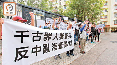 示威者踩上漢奸黎寓所門外拉起橫額抗議，並高叫「黑金政治　禍亂香港」口號。（蘇偉明攝）