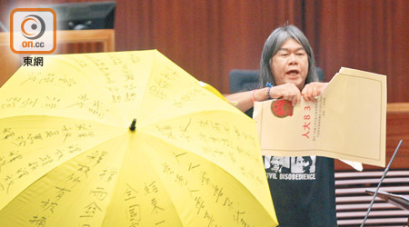 梁國雄撐着黃傘宣誓，並撕爛象徵「八三一」決議的道具。（資料圖片）