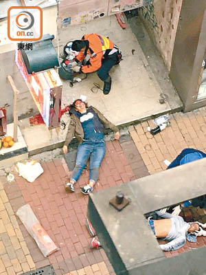 救護員為受傷工人（右）及女途人（左）急救。（讀者提供）
