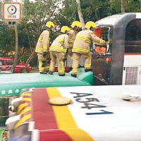 消防員在巴士上層車尾救出被困傷者。（劉子文攝）