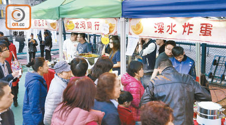 深水埗楓樹街球場辦美食墟，不少食物以折扣價發售惠及基層。（何駿軒攝）