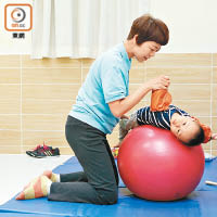 子瑨在物理治療師協助下，在訓練球上改善肌肉張力。