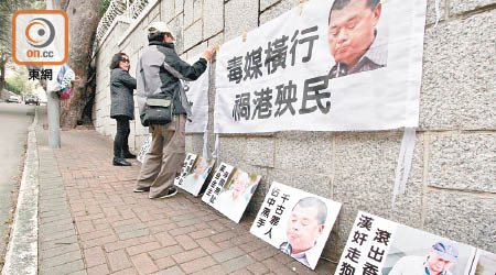 兩名示威者喺牆上張貼橫額，譴責漢奸黎禍港殃民。