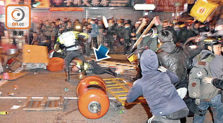 圍毆<br>旺角暴亂期間一名交通警倒地後（箭嘴示），繼續被多名暴徒投擲垃圾桶等雜物。