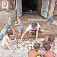 印度小孩在地上畫畫，分享快樂。