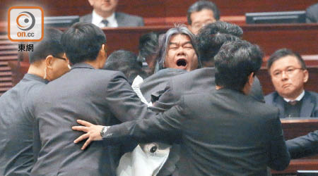 梁國雄在陳茂波宣讀預算案期間衝出主席台抗議，被主席下令驅趕出會議廳。（胡家豪攝）