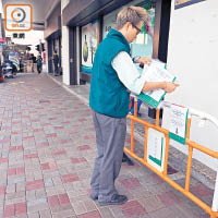 香港郵政職員在當日早上八時零五分，收回膠欄上有關出售新郵票的告示。