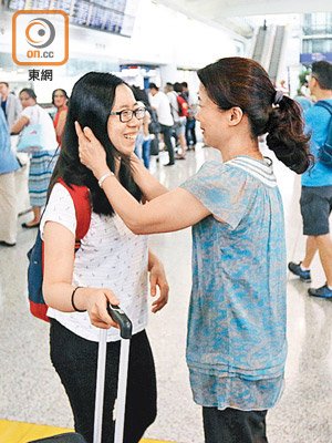 乘客范小姐（左）平安抵港，前來接機的家人即與她相擁。