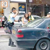 警員手持警棍，將長髮女乘客拉出車外。（讀者提供）