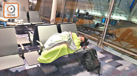 登機閘外乘客無奈苦候，有人疲極在椅上休息。（乘客提供）