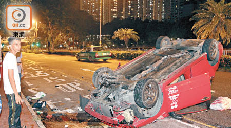 私家車四輪朝天，司機（左）手腳擦傷。（文健雄攝）