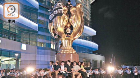 香港眾志、社民連及人民力量廿多名成員昨再突襲灣仔金紫荊廣場，圍坐紫荊花雕塑及掛橫額。