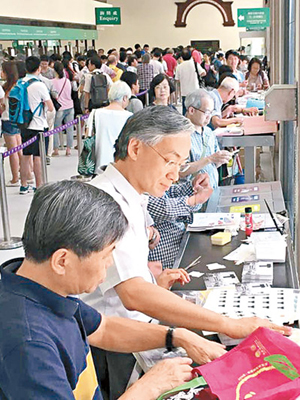 有市民喺郵局發現岑智明（左二），當時佢正小心處理數字颱風信號百周年紀念郵票。（互聯網圖片）