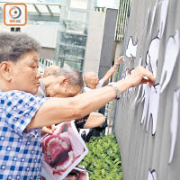 請願人士將牙科車及牙齒的圖片貼到公民廣場的圍欄上。