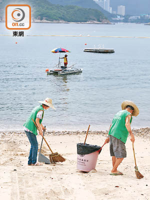清潔工人忙於清理被沖上泳灘的棕櫚硬脂。（黃雄攝）