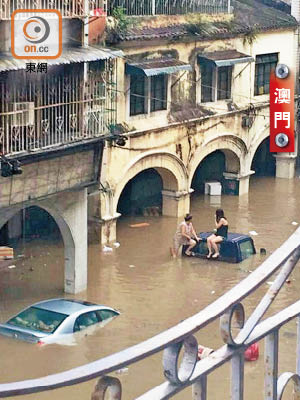 澳門多條馬路成澤國，有市民坐在被淹沒的汽車頂暫避。（讀者提供）