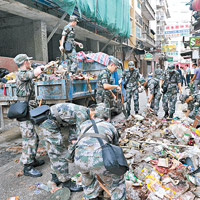 十月初五街<br>官兵們合力把地面雜物剷上貨車運離。（中新社圖片）