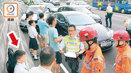 警方及救護員到場救援，錯過開學禮的男童坐在一旁（箭嘴示）。（張開裕攝）