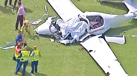飛機嚴重損毀，救援人員於座位上掩蓋白布。（電視畫面）