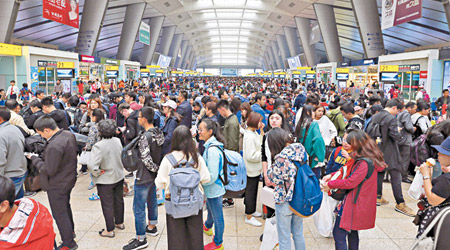 北京南站有大批遊客排隊乘火車，車站大堂擠滿旅客。（中新社圖片）