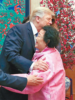 特朗普（左）與李容洙（右）擁抱。（互聯網圖片）