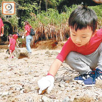 年紀小小的Victo，在沙堆中挖出魚網夾子和發泡膠膠粒。