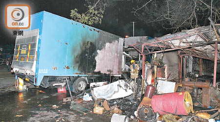 鐵皮屋旁兩輛貨車被焚毀。（楊日權攝）