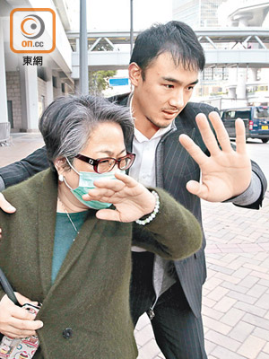 周向榮妻子（左）昨在兒子陪同下離開法院，全程迴避傳媒追訪。（羅錦鴻攝）