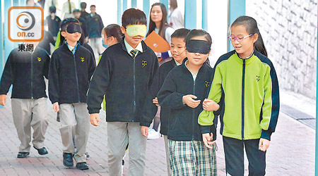 學生戴上眼罩，體驗失明人士漆黑的世界，並由同伴運用領路法，帶領他們向前走。